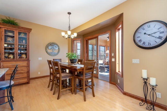 dining room featuring light wood-type flooring, baseboards, and an inviting chandelier