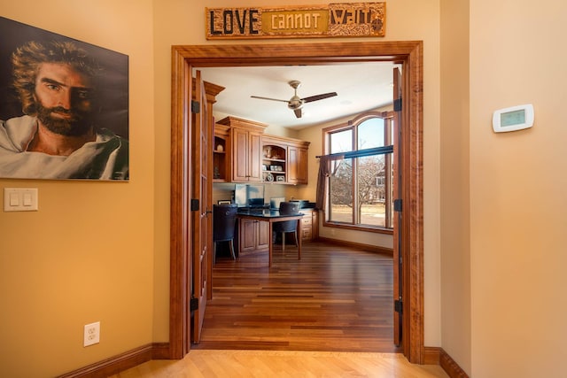 corridor featuring baseboards and light wood finished floors