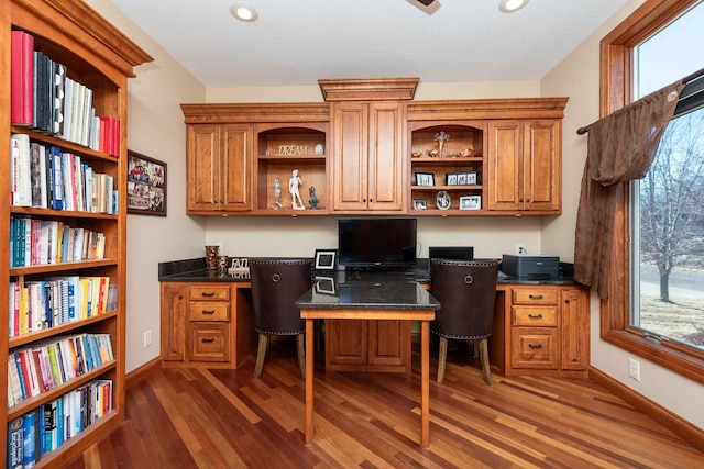 office area featuring plenty of natural light, dark wood-type flooring, and built in study area