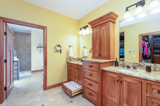 full bath featuring a walk in shower, tile patterned flooring, vanity, baseboards, and a walk in closet