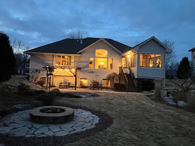 rear view of property with stairway, a sunroom, a patio area, and a fire pit