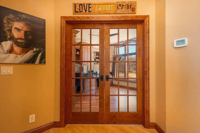 entryway featuring french doors, wood finished floors, and baseboards