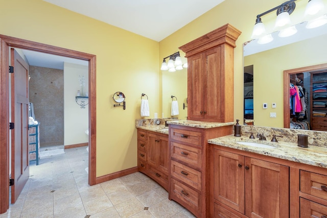 bathroom with baseboards, tile patterned flooring, walk in shower, a walk in closet, and vanity