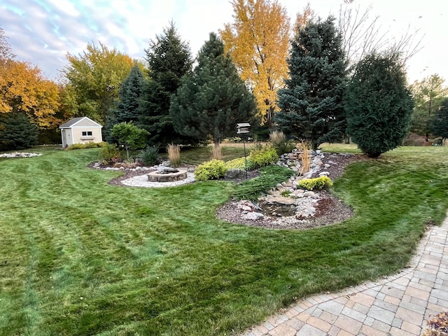 view of yard with a fire pit, a storage unit, and an outdoor structure