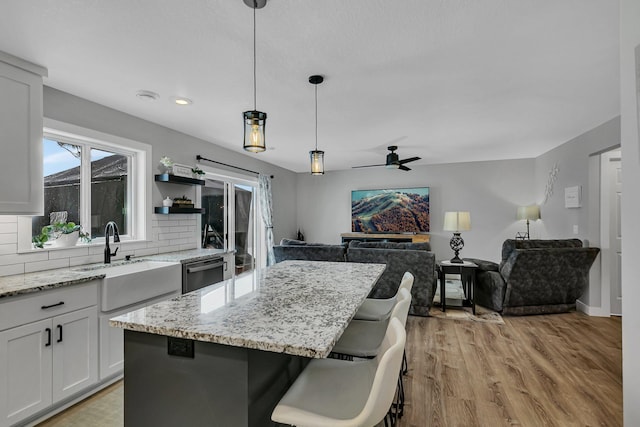 kitchen featuring sink, a kitchen breakfast bar, white cabinets, a kitchen island, and decorative light fixtures