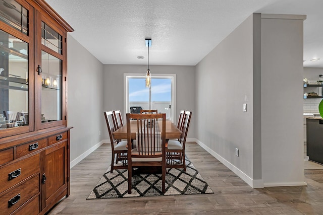 dining room featuring a textured ceiling and light hardwood / wood-style flooring