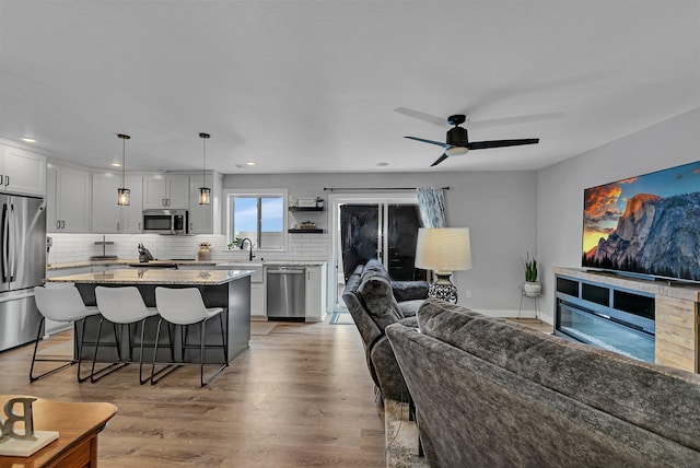 living room featuring hardwood / wood-style floors, a fireplace, sink, and ceiling fan