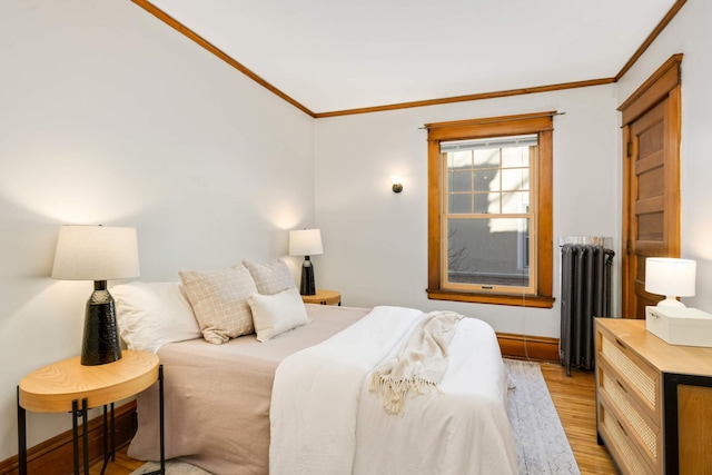 bedroom featuring radiator, light wood-type flooring, baseboards, and crown molding