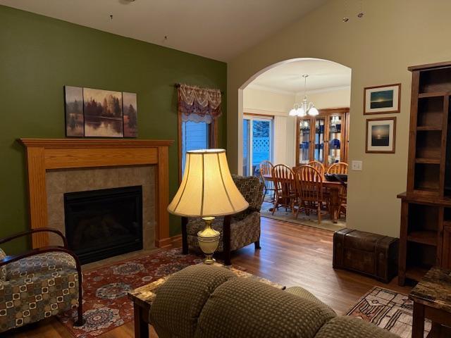 living room with wood-type flooring, lofted ceiling, a notable chandelier, and a fireplace