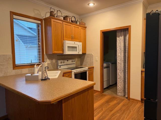 kitchen featuring crown molding, white appliances, decorative backsplash, kitchen peninsula, and light wood-type flooring