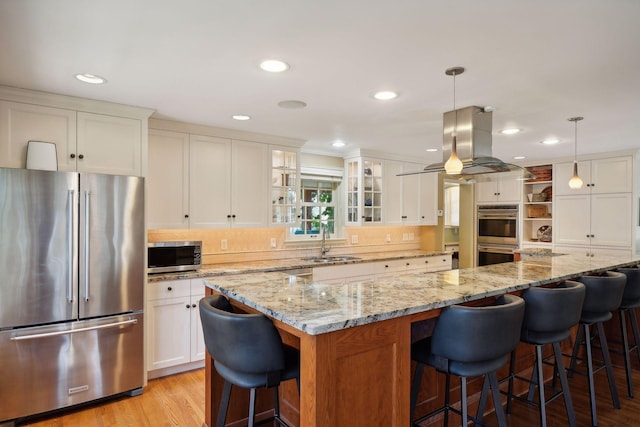 kitchen with white cabinetry, hanging light fixtures, island exhaust hood, stainless steel appliances, and a large island