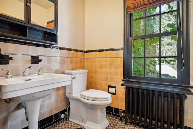 bathroom with radiator, tile walls, and toilet