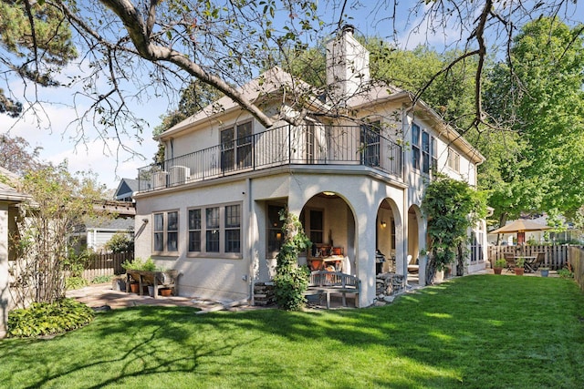 back of house featuring a yard, a patio area, and a balcony