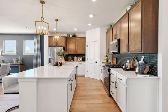 kitchen with sink, a center island with sink, appliances with stainless steel finishes, light hardwood / wood-style floors, and white cabinets