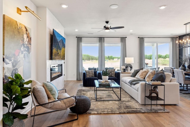 living room with ceiling fan with notable chandelier and light wood-type flooring