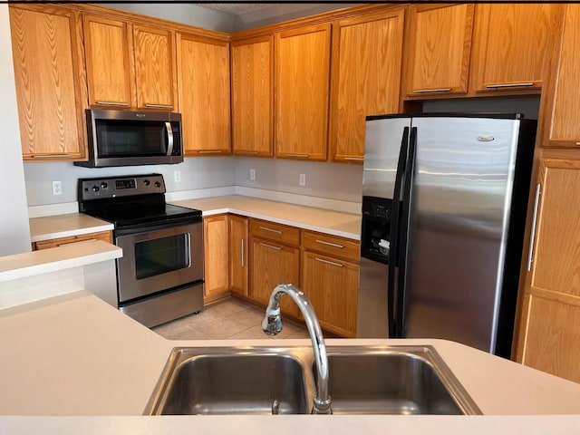 kitchen with light countertops, light tile patterned floors, appliances with stainless steel finishes, and a sink