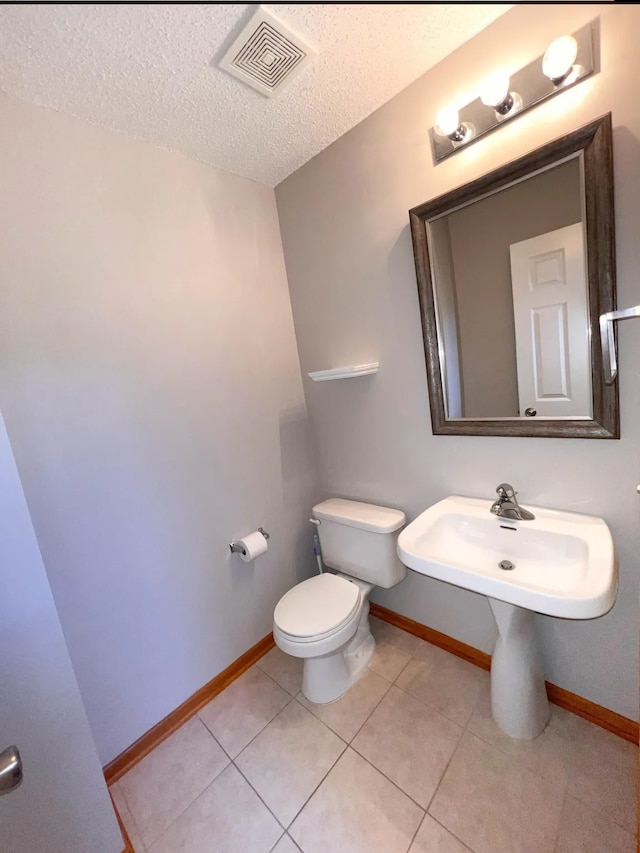 bathroom featuring baseboards, visible vents, a textured ceiling, tile patterned floors, and toilet