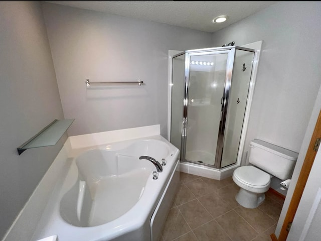 bathroom featuring tile patterned flooring, toilet, a garden tub, a stall shower, and a textured ceiling