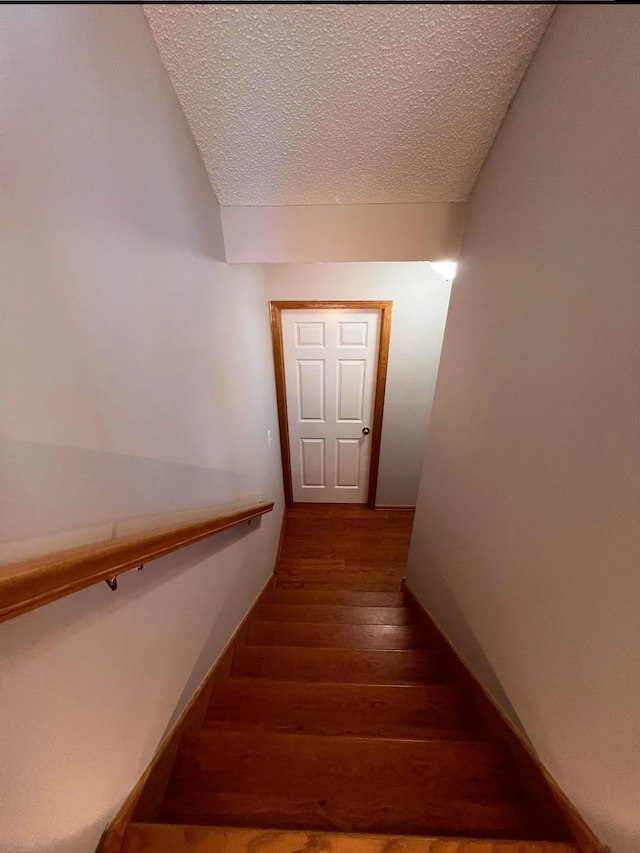 staircase with hardwood / wood-style flooring, baseboards, and a textured ceiling