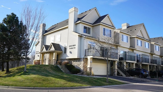 view of front facade featuring a front lawn, stairway, a chimney, stone siding, and driveway