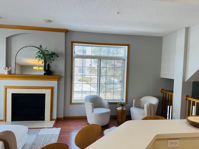 living room with a fireplace with flush hearth, wood finished floors, baseboards, and a textured ceiling