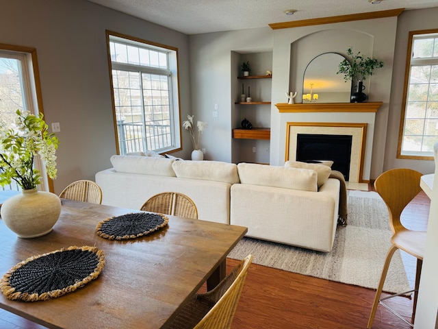 dining room with built in features, plenty of natural light, a fireplace, and wood finished floors