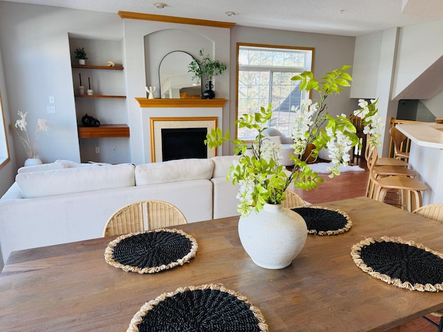 dining area featuring a fireplace, a textured ceiling, and built in shelves