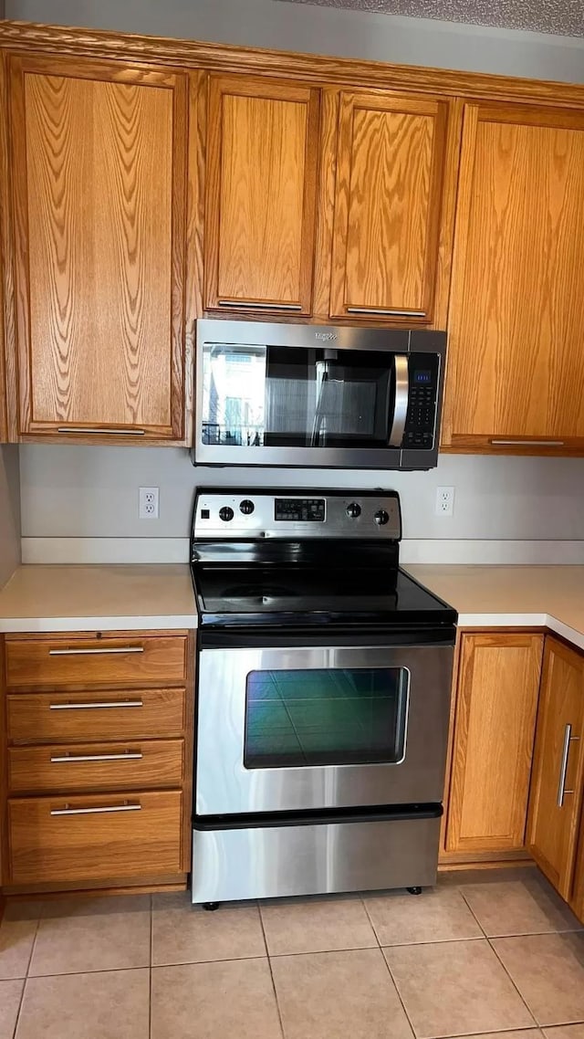 kitchen with light tile patterned floors, stainless steel appliances, and light countertops