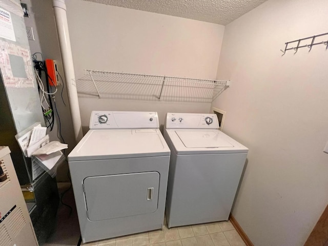 laundry area with laundry area, washer and dryer, a textured ceiling, and baseboards