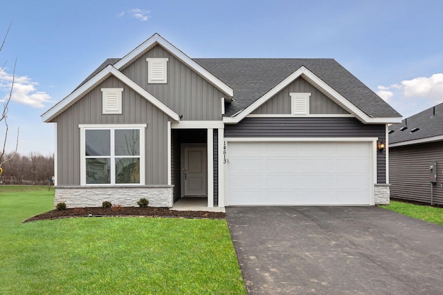 view of front of property with a front lawn, aphalt driveway, stone siding, a shingled roof, and a garage