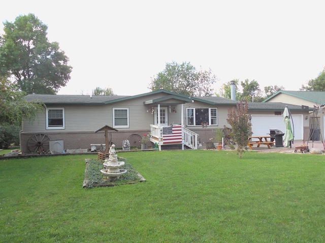 rear view of property with a yard, brick siding, and an attached garage