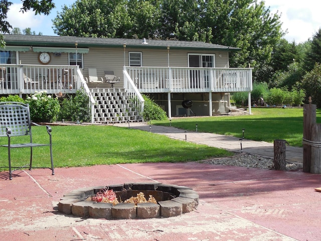 exterior space featuring stairway, a lawn, a fire pit, and a deck