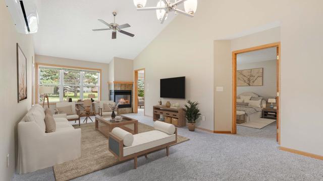 living room with an AC wall unit, ceiling fan with notable chandelier, high vaulted ceiling, a tiled fireplace, and light carpet