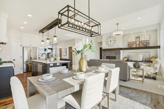 dining area with sink, a stone fireplace, and hardwood / wood-style flooring