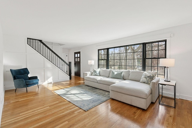 living room with stairs, wood finished floors, and a decorative wall