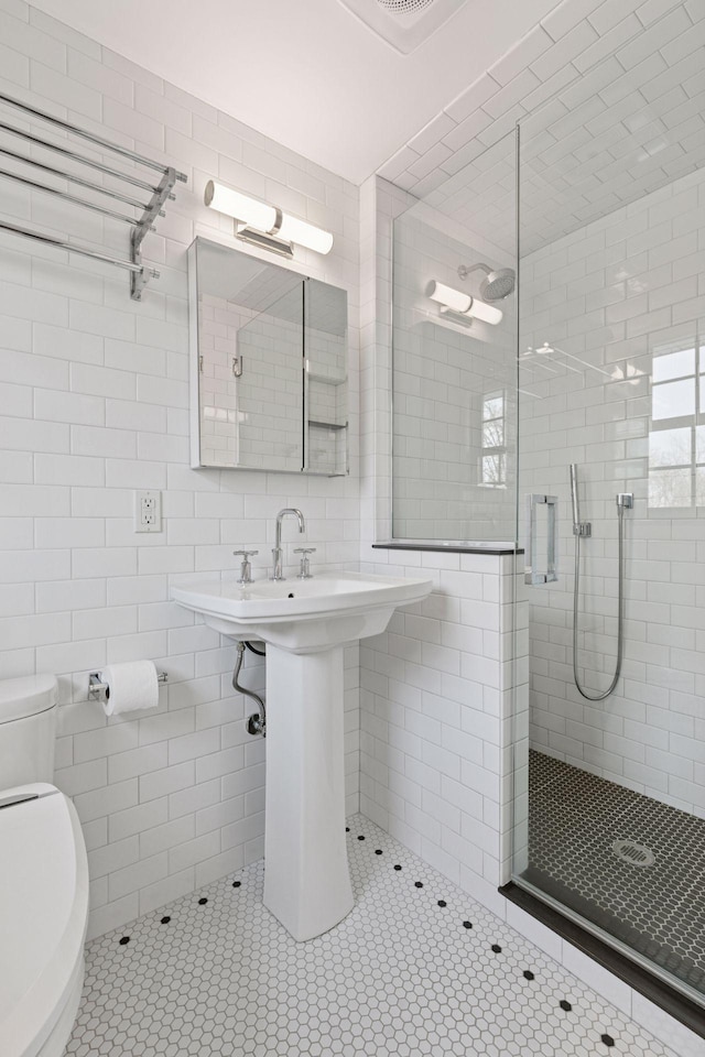 full bath with toilet, tile walls, backsplash, a shower stall, and tile patterned floors