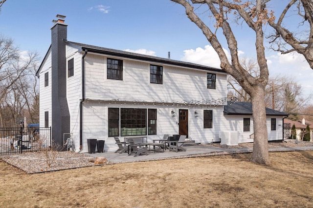 back of property with a patio, a chimney, fence, and a lawn