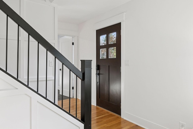 foyer featuring light wood-type flooring, baseboards, and stairs