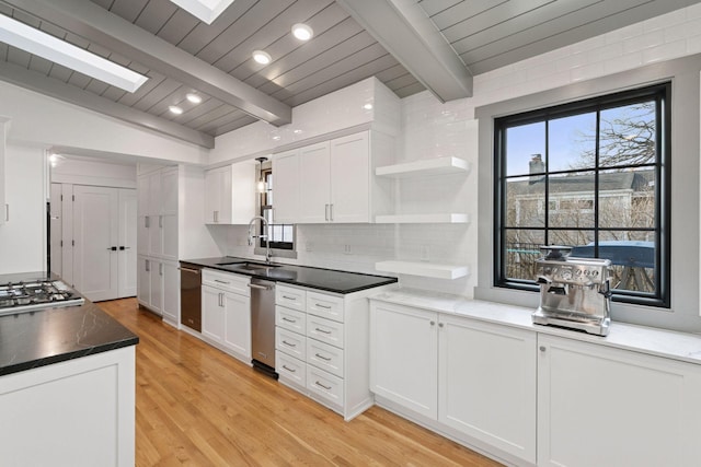 kitchen with tasteful backsplash, white cabinets, light wood-style floors, open shelves, and a sink