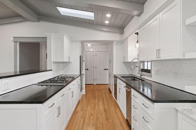 kitchen featuring vaulted ceiling with beams, a sink, white cabinetry, appliances with stainless steel finishes, and backsplash