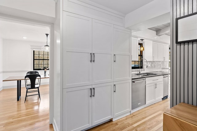 kitchen featuring light wood-style flooring, a sink, white cabinetry, decorative backsplash, and dishwasher