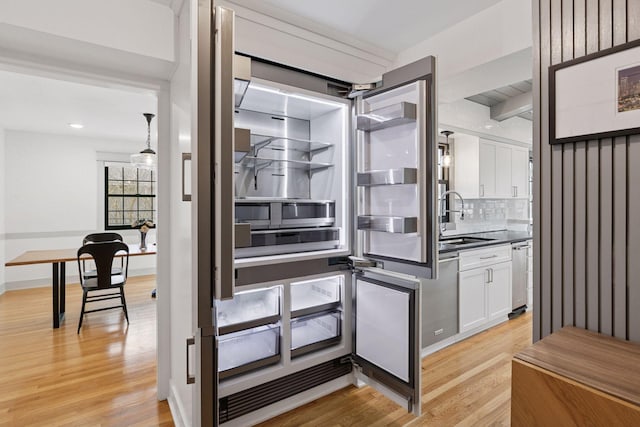 interior space featuring dishwasher, light wood-style flooring, backsplash, and a sink