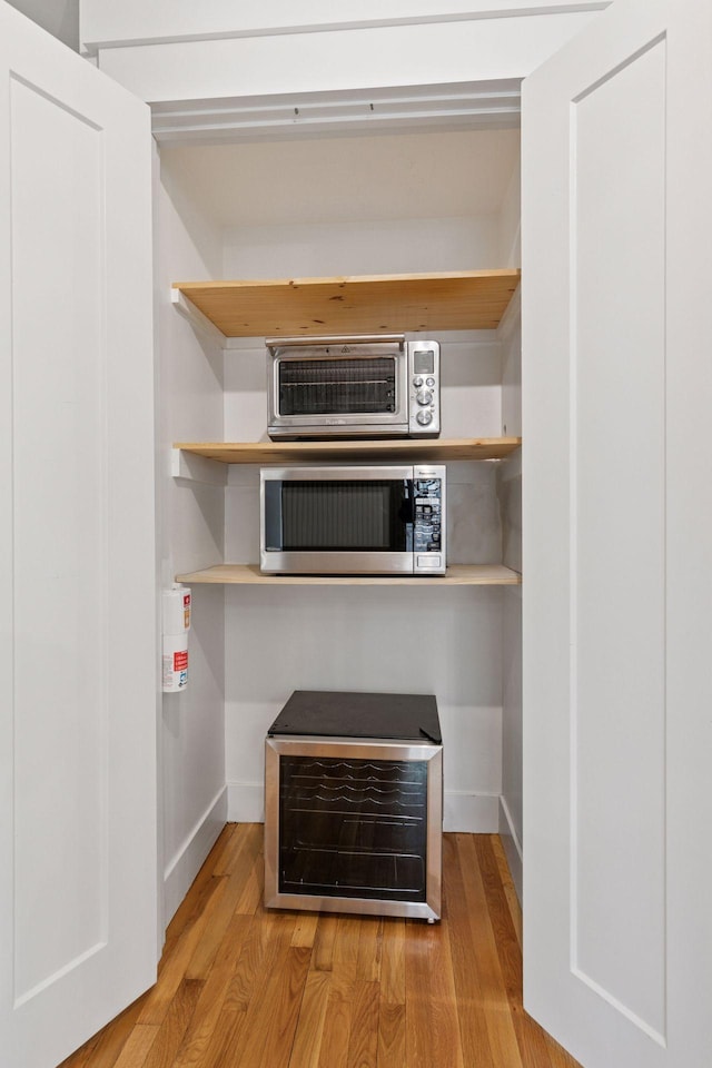 interior space featuring light wood-type flooring, baseboards, stainless steel microwave, and open shelves