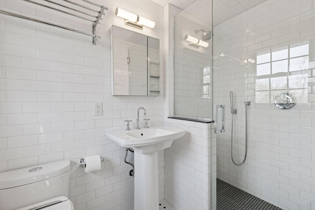 bathroom featuring toilet, a stall shower, and tile walls