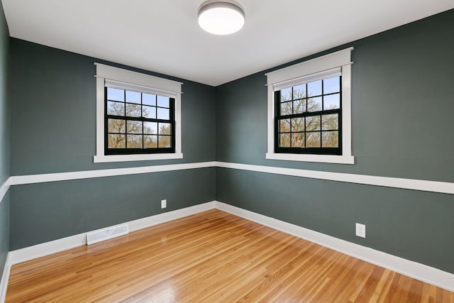 empty room featuring visible vents, baseboards, and wood finished floors