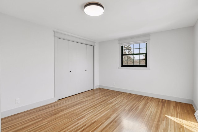 unfurnished bedroom with a closet, baseboards, and wood finished floors