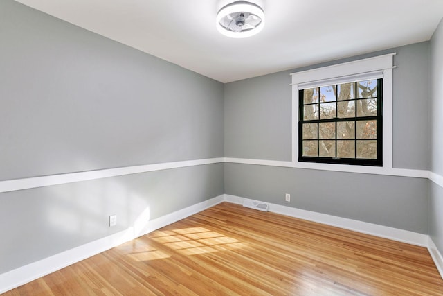 empty room with baseboards, visible vents, and wood finished floors