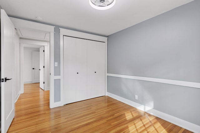 unfurnished bedroom with baseboards, a closet, and light wood-style floors