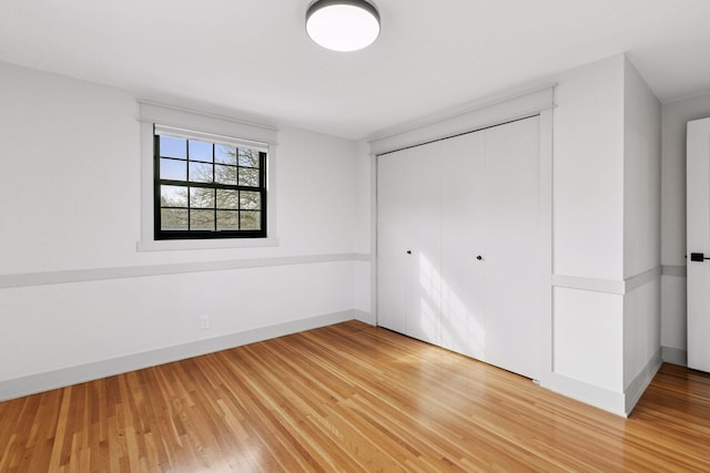 unfurnished bedroom with a closet, light wood-style flooring, and baseboards