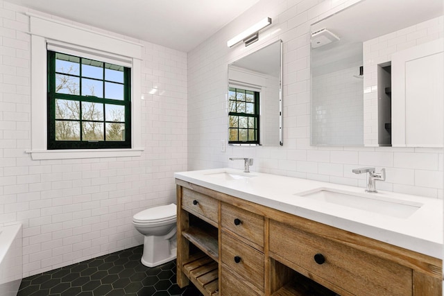 bathroom featuring tile patterned flooring, a sink, toilet, and tile walls